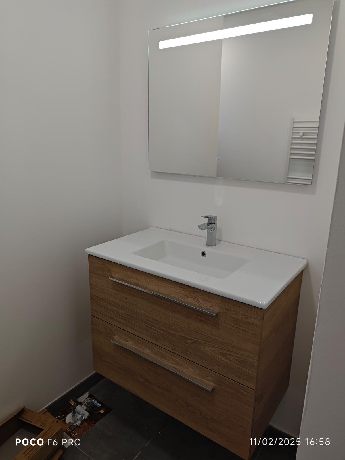Vasque et miroir lumineux installés dans une salle de bain rénovée